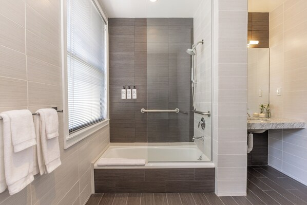 A modern bathroom with a bathtub, shower, and a vanity with a marble countertop. - Hotel Clark (Los Angeles)