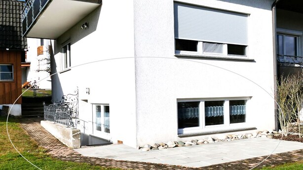 Un bâtiment moderne à deux étages, avec une façade blanche, un balcon et une allée pavée.