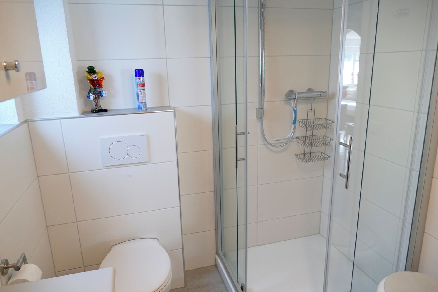 A modern bathroom with a glass-enclosed shower, a toilet, and a sink.