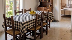 A dining area with a checkered tablecloth, wooden chairs, a bookshelf, and a view through a sliding door to an outdoor balcony. - Laura's little houses: second floor 1 (Palermo)