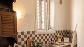 A compact kitchen with a checkered backsplash, a window with blinds, a gas stove, and a sink. - Laura's little houses: second floor 1 (Palermo)