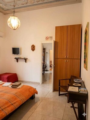 Une chambre à coucher comprenant un lit, une télévision, une armoire et un bureau avec une chaise.