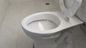 Un baño moderno con inodoro blanco, zona de ducha y desagüe visible.