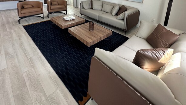 Un salon moderne comprenant un canapé, deux fauteuils, une table basse et un téléviseur.