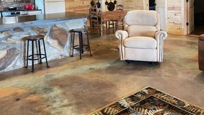 L’intérieur d’un chalet rustique comprend une cuisine, un coin repas et un grand tapis orné de motifs naturels.