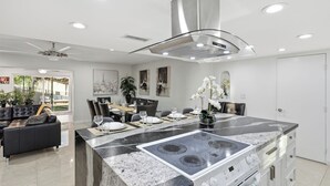 A modern kitchen with a central island, built-in stove, and dining area with chairs and table set for six. - Two Homes w/ Pool, 8BR Mesa Retreat, Sleeps 24 (Mesa)