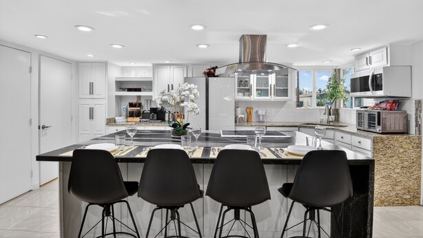 A modern kitchen with white cabinets, a granite countertop, and a central island with bar stools. - Two Homes w/ Pool, 8BR Mesa Retreat, Sleeps 24 (Mesa)