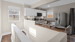 Una cocina moderna con armarios blancos, un refrigerador de acero inoxidable y un microondas.