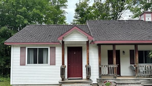 A two-story house with a front porch, a red door, and a mailbox.
