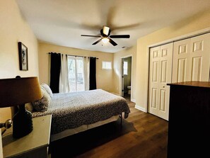 Ein Schlafzimmer mit einem Bett, Deckenventilator, Nachttisch, Lampe, Kommode und Kleiderschrank.