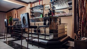 Un coin bar avec un tabouret de bar en cuir noir, le logo de BMW et une vitrine.