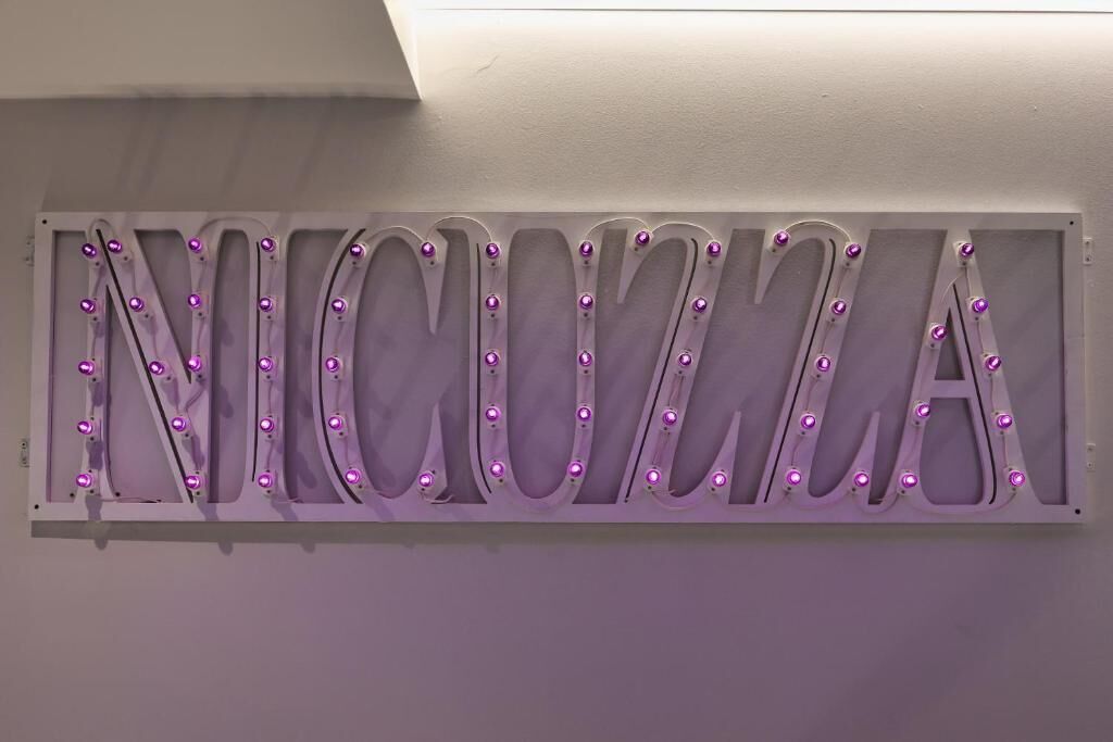 A wall with illuminated letters spelling "ENICOMIA".