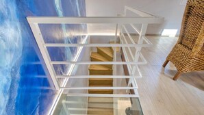 A modern staircase with glass railings and wooden steps, leading to an upper level. - VFH Blue Breeze Holiday Home (Porticello)