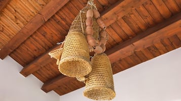 A ceiling with wooden beams and a woven basket chandelier.