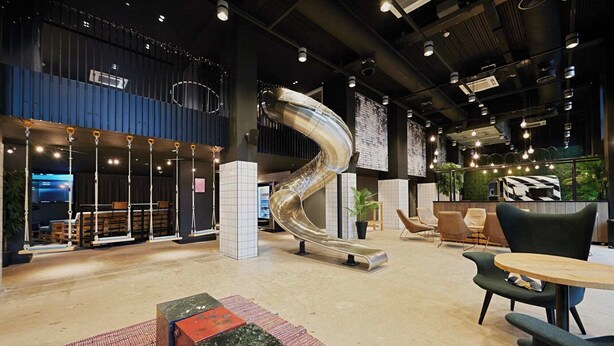 A modern interior with a curved slide, seating areas, and a bar. - Student Only West End (Glasgow)