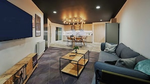 A modern living room with a sofa, a coffee table, and a TV on the wall. - Student Only West End (Glasgow)