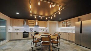 A modern kitchen with a round dining table, wooden cabinets, and a stainless steel refrigerator. - Student Only West End (Glasgow)
