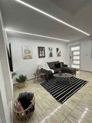 Un salon moderne avec un canapé, une table basse et des œuvres d’art accrochées au mur.