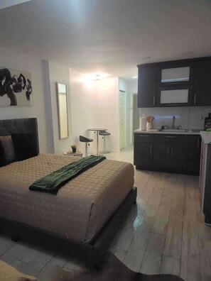 Ein modernes Hotelzimmer mit einem großen Bett, einer kleinen Küchenzeile und einem Esstisch.
