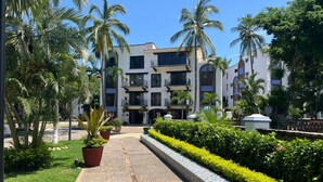 Un hôtel à plusieurs étages doté d’une cour intérieure, entourée de palmiers et d’une végétation luxuriante et bien entretenue.