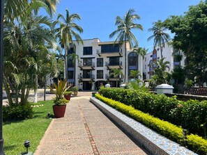 Un hôtel à plusieurs étages doté d’une cour intérieure, entourée de palmiers et d’une végétation luxuriante et bien entretenue.