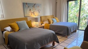 A hotel room with two beds, a balcony with a view of palm trees, and a painting of birds on the wall. - Puerto de Luna: Double Room with Kitchen & Pool Access (Puerto Vallarta)