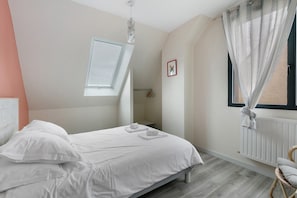 Un dormitorio con cama, una ventana con cortinas, un radiador y una mesita de noche pequeña.