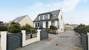 Ein Wohnhaus mit befahrbarer Allee und geschlossenem Tor, zwei Stockwerken und einem angelegten Garten.