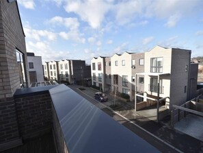 Un filare di moderni palazzi residenziali, cielo sereno e un'auto parcheggiata in primo piano.