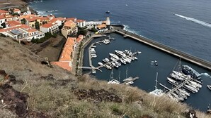 Eine Küstenstadt mit einem Yachthafen, Häusern mit roten Dächern und blauem Himmel.