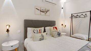 Une chambre à coucher comprenant un lit, des tables de chevet, un climatiseur fixé au mur et un luminaire fixé au mur.