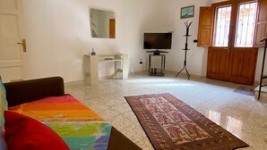 Amplia sala de estar con sofá, televisor, mesa de centro y alfombra estampada.