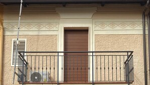 Un edificio de dos pisos con un balcón, una puerta marrón y un buzón con el número 31.
