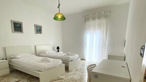 Un dormitorio con dos camas, un escritorio, una silla, una lámpara y una luz en el techo.
