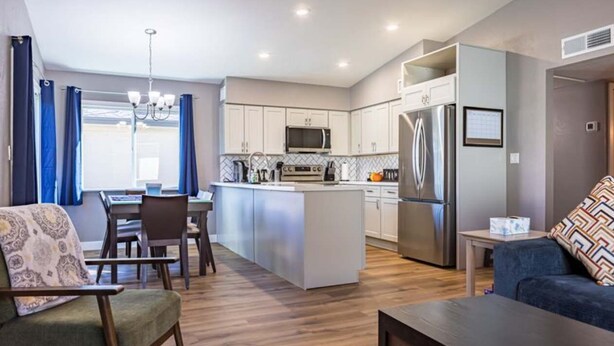 A modern kitchen with a central island, stainless steel appliances, and a dining area with a table and chairs. - Cozy townhouse with community pool, heart of Tempe near ASU (Tempe)