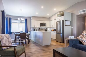 Una cocina moderna con una isla central, electrodomésticos de acero inoxidable y un comedor con mesa y sillas.