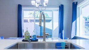 A modern kitchen with a stainless steel sink, blue curtains, and a chandelier. - Cozy townhouse with community pool, heart of Tempe near ASU (Tempe)