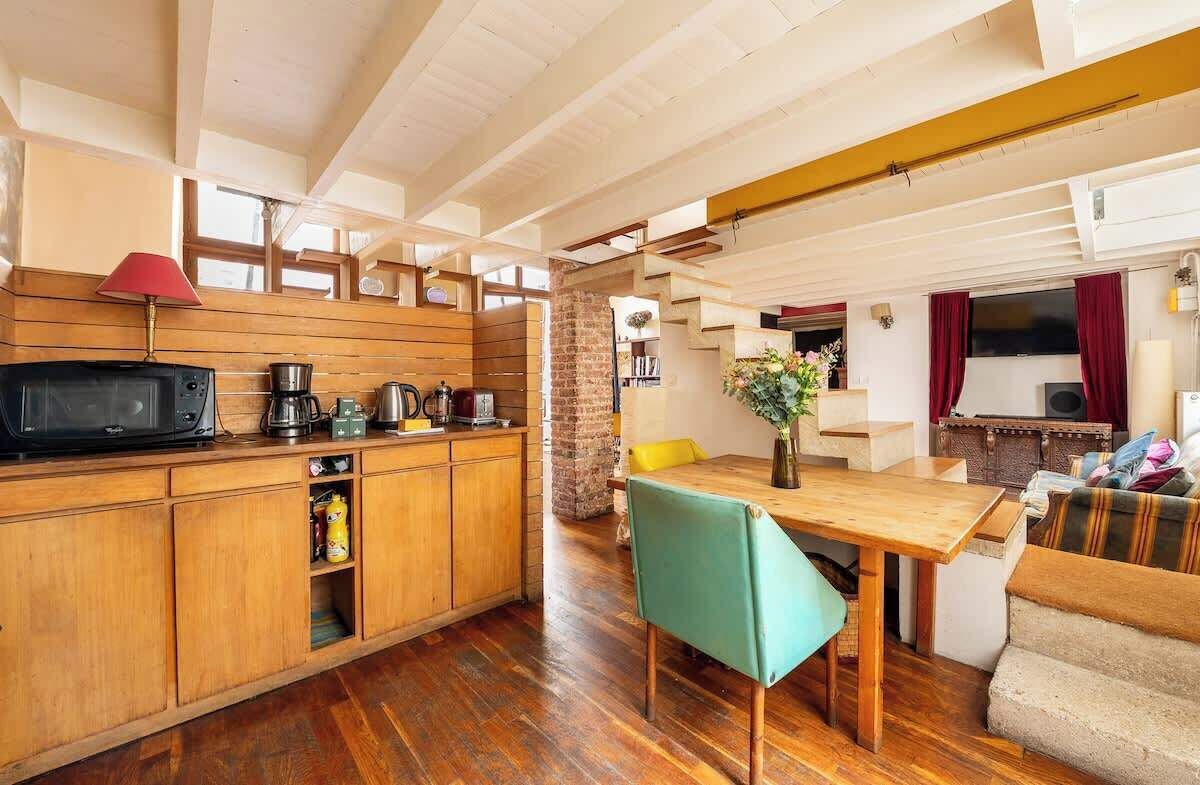 Une cuisine de taille réduite, avec des meubles de rangement en bois, une table à manger et un canapé.