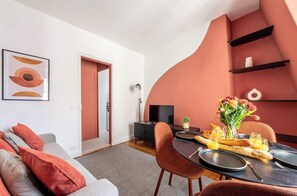 Ein modernes Wohnzimmer mit einer Couch, einem Esstisch gedeckt mit Tellern, Gläsern und einer Blumenvase.