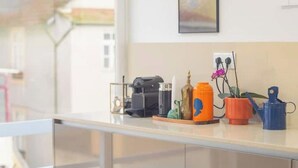 Una encimera de cocina con una cafetera, una pequeña planta y un molinillo de café.
