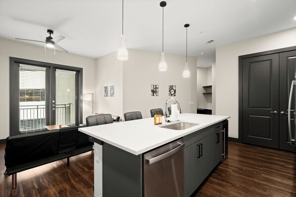 A modern kitchen with a central island, a dining area with a bench, and a ceiling fan.