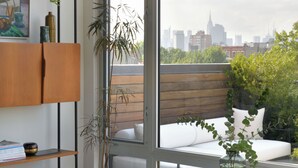 A modern living room with a large window, a wooden bench, a glass coffee table, and a white sofa.