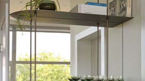 A modern interior with a wooden counter, a glass display case, and a shelf with books and a potted plant.