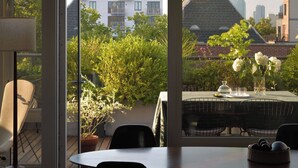 A modern dining area with a large window overlooking a cityscape and greenery.