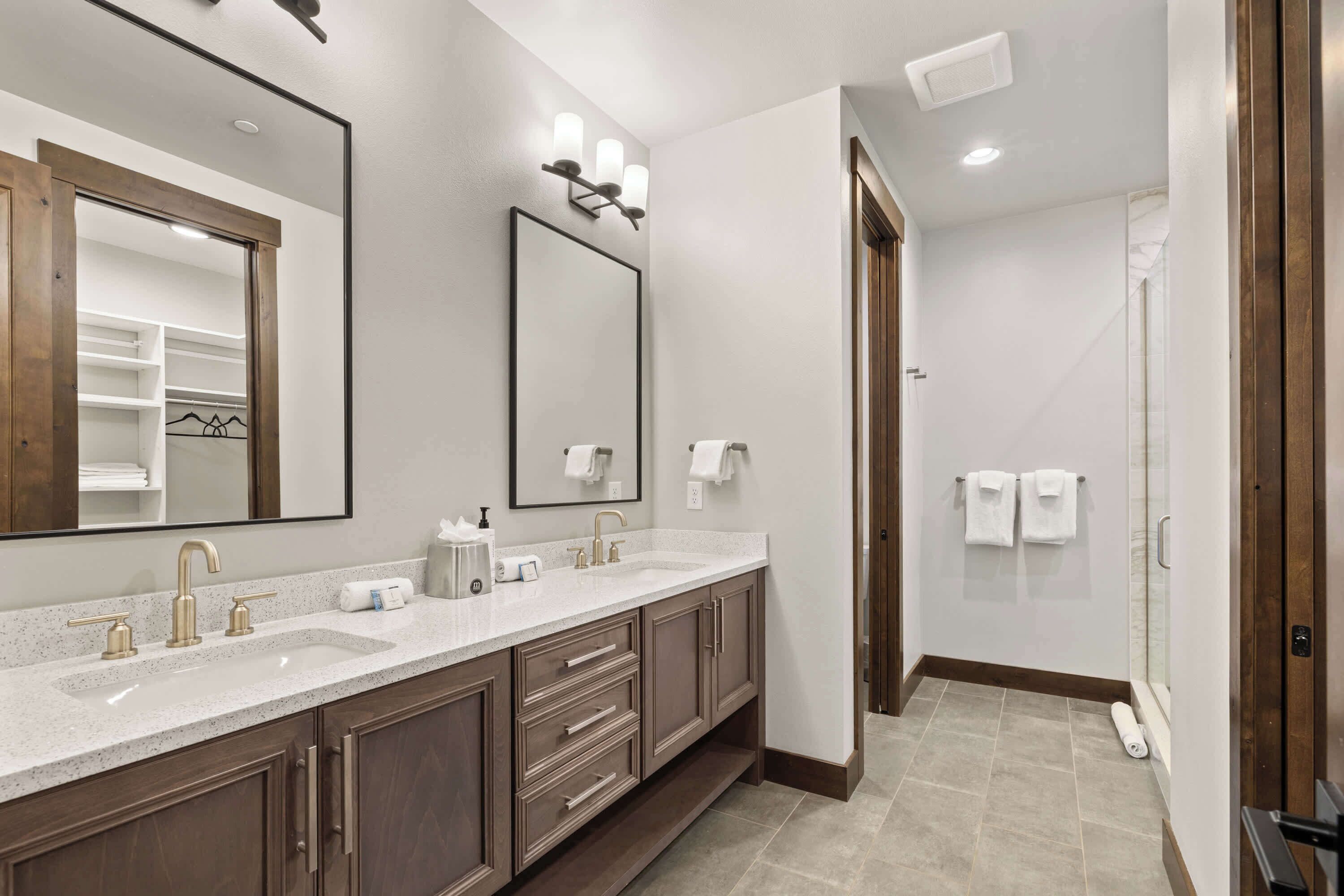 A modern bathroom with two sinks, a large mirror, and a shower area.