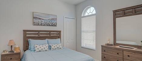 Un dormitorio con cama, mesita de noche de madera, cómoda y ventilador de techo.