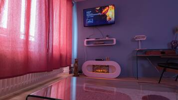 Una sala de estar moderna con un televisor de pantalla plana montado en la pared, una chimenea y una mesa de centro de vidrio.
