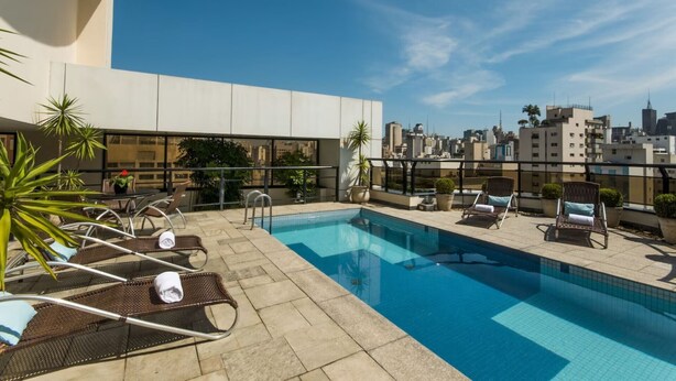Une piscine sur le toit, avec des chaises longues et des plantes en pot.