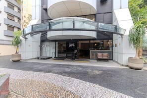 A modern building with a glass entrance and a covered walkway. - Moderno Studio nos Jardins Funcional e com Lazer (São Paulo)