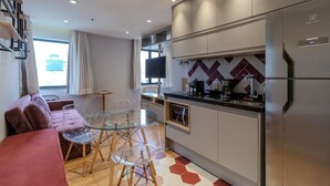 Une cuisine moderne dotée d’un réfrigérateur encastré, d’un téléviseur à écran plat et d’un coin repas avec une table et des chaises en verre.